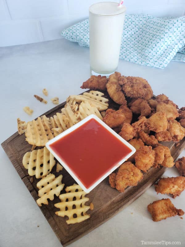 Polynesian Sauce chick fil a copycat in a square bowl surrounded by French fries and chicken with a frosted lemonade in the background. 