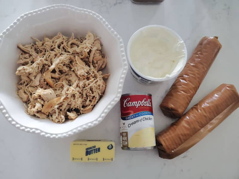 Shredded chicken in a white bowl, sour cream, ritz crackers, butter, cream of chicken soup
