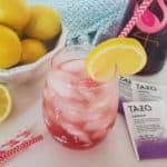 Copycat Starbucks Passion Tea Lemonade in a mason jar next to Tazo Passion tea bags, and a bowl of lemons