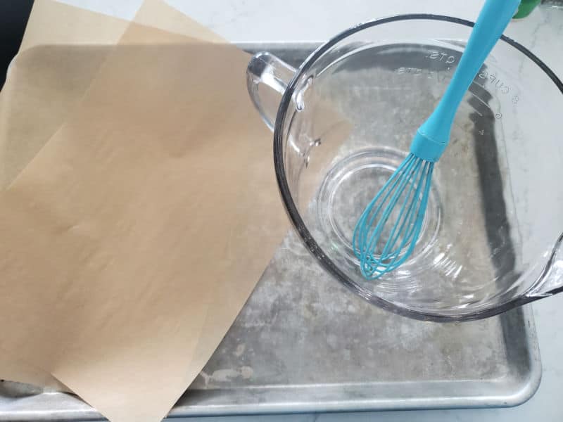 baking sheet with parchment paper, glass bowl, and whisk