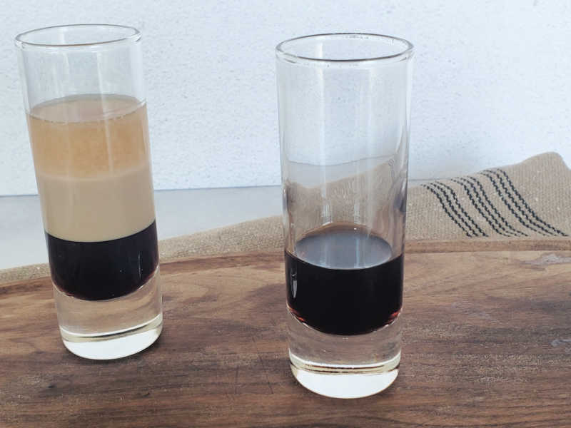 Two shot glasses one with a Duck fart shot complete and another with one layer of brown liquid