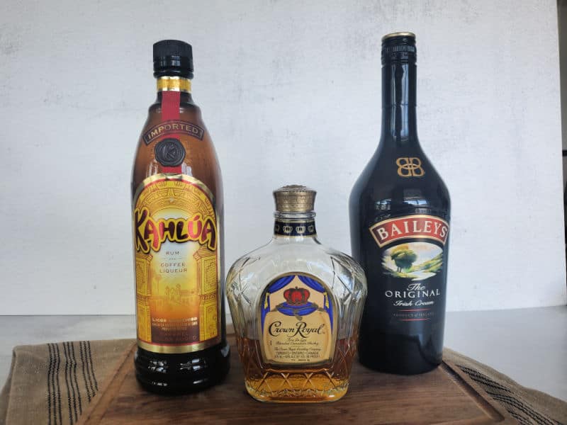 Kahlua, Crown Royal, and Baileys Irish Cream bottles on a wooden board. 
