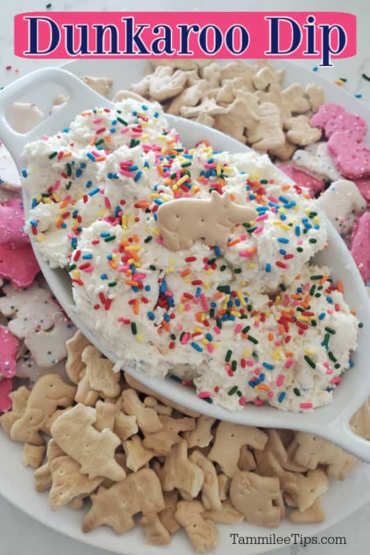 Dunkaroo dip text over a white bowl filled with dip topped with an animal cracker sitting on a white plate filled with animal crackers. 