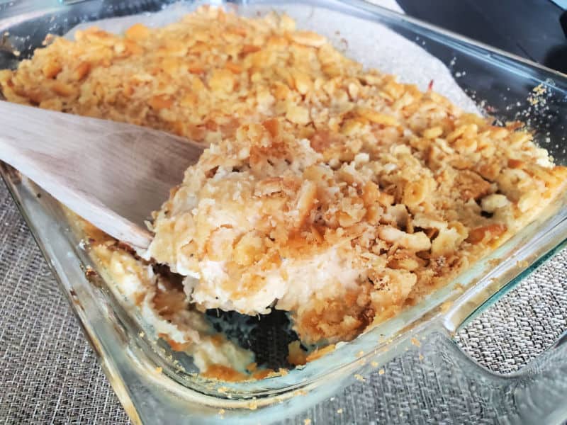 wooden spoon scooping ritz chicken casserole out of a baking dish