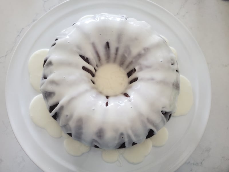 icing glaze covering a bundt cake on a white platter