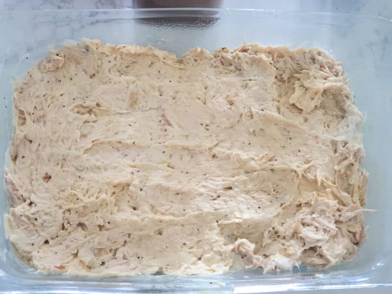 shredded chicken casserole mixture spread in a glass casserole dish