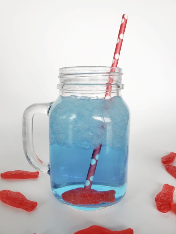 Blue Sonic Ocean Water Drink in a mason jar glass with a red polka dot straw and Swedish Fish