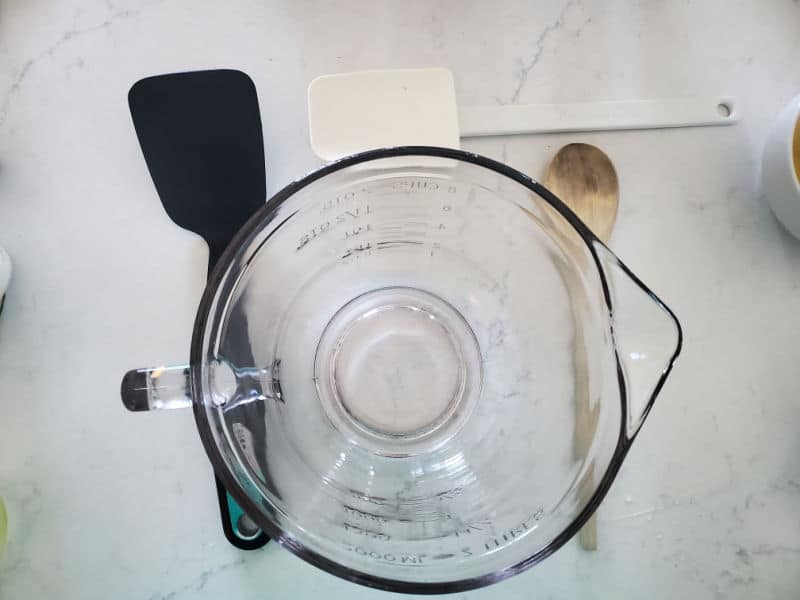 glass batter bowl, spatula, wooden spoon, and pancake turner on a white counter 