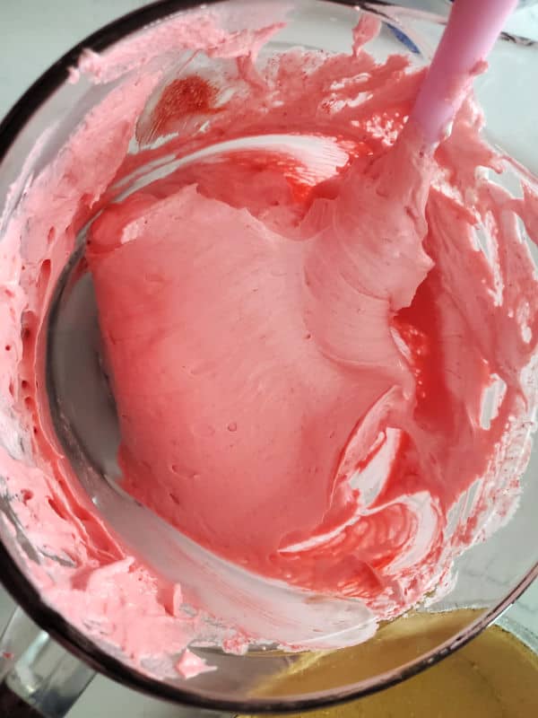 Kool Aid Pie pink mixture in a glass bowl with a spatula