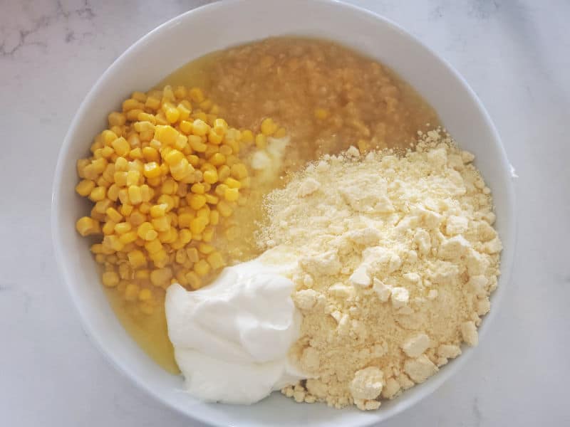 Creamed Corn Casserole ingredients in a white bowl before mixing