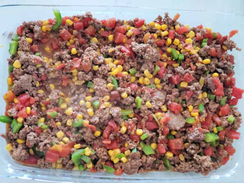 ground beef, tomatoes, corn, and bell peppers in a casserole dish