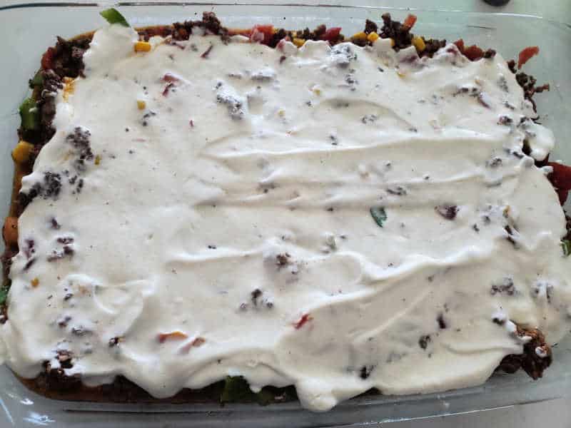 sour cream mixture over ground beef and vegetables in a casserole dish