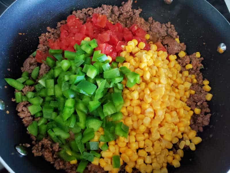 cooked ground beef with rotel, corn, and bell peppers in a large skillet