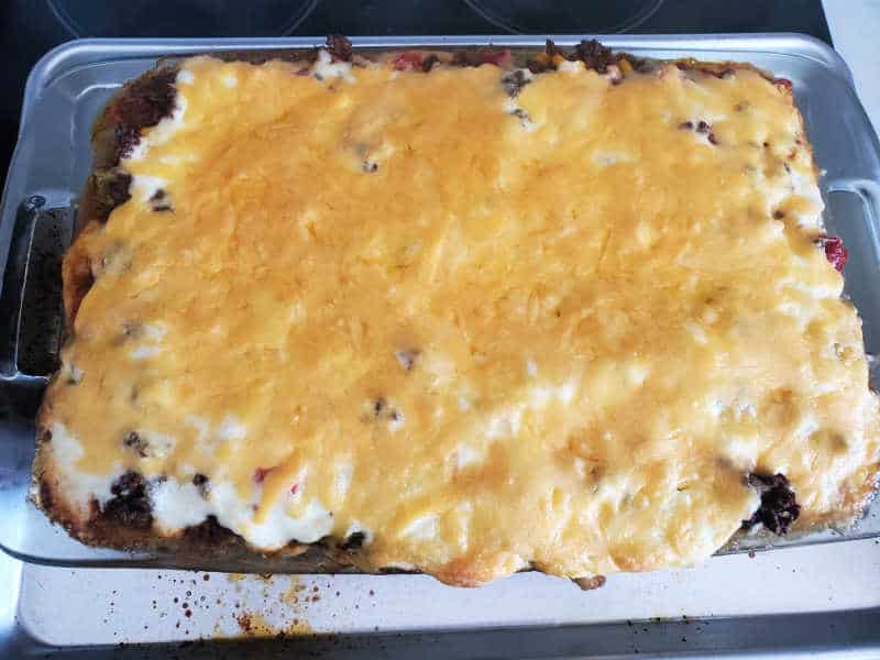 melted cheddar cheese over a beef casserole in a casserole dish. 