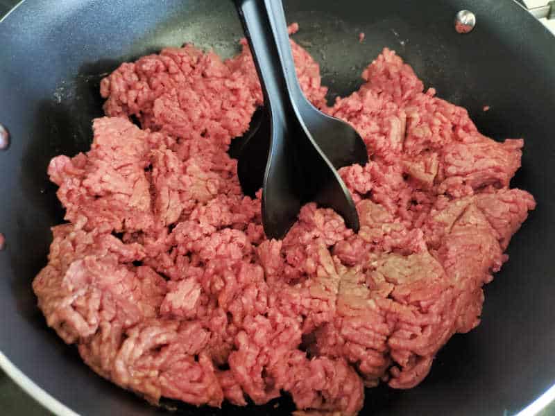 Ground beef cooking in a skillet with a meat chopper