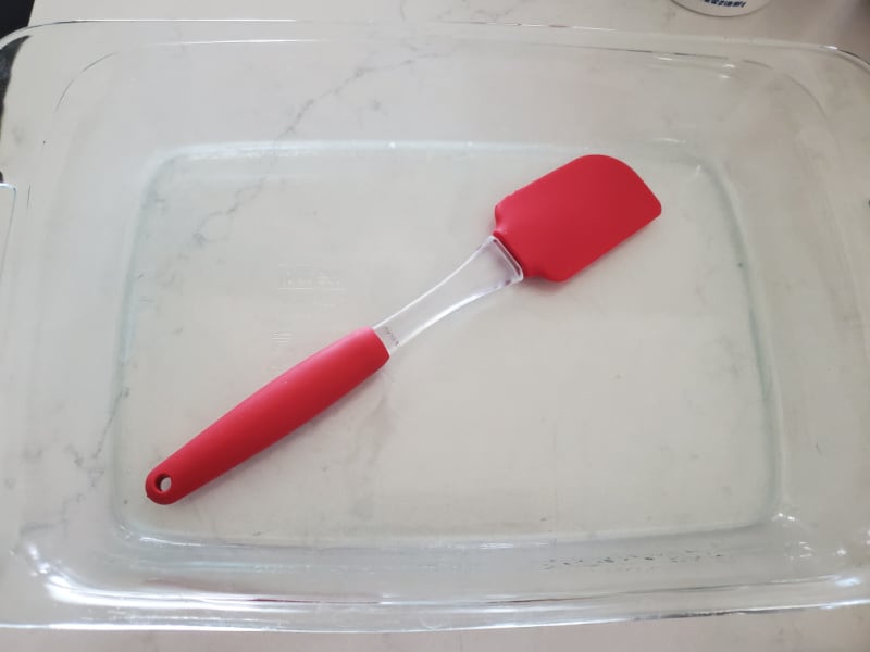 Red spatula in a glass casserole dish