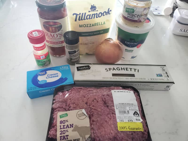 garlic powder, cream cheese, Rao's marinara, Tillamook Mozzarella, Minced Garlic, Ricotta cheese, spaghetti noodles, and ground beef on a white counter