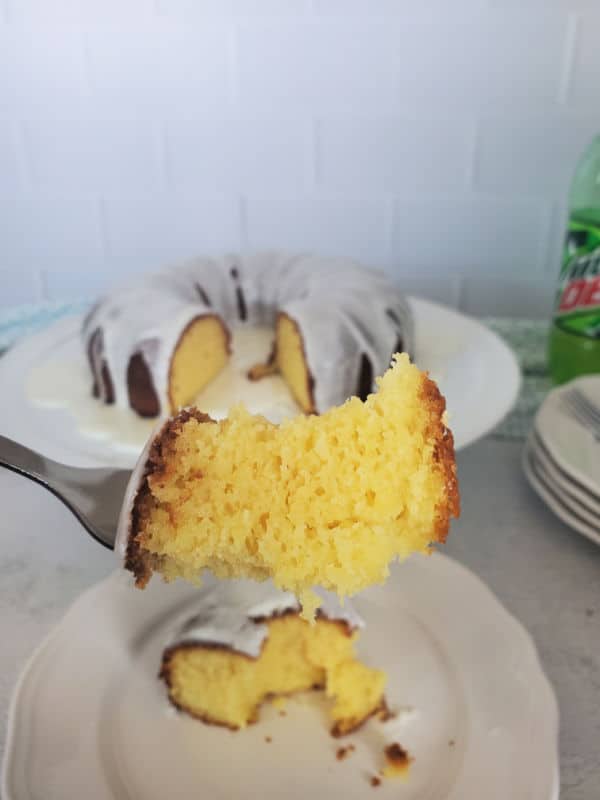 Fork holding a piece of MTN Dew cake over a plate next to a mountain dew Bundt Cake