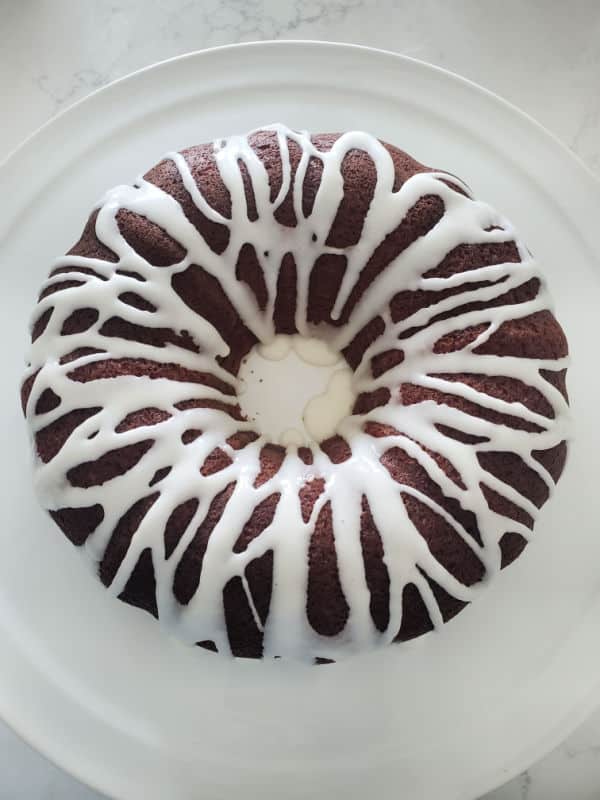 white icing over a bundt cake on a white platter