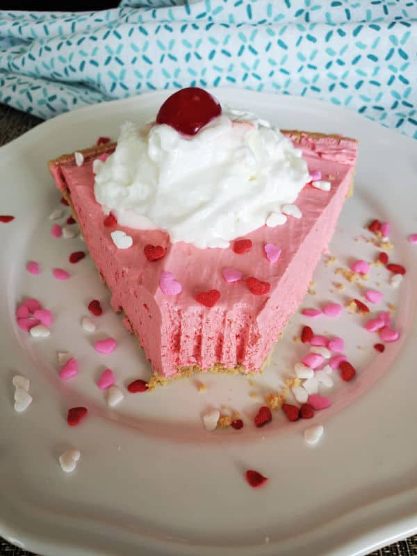 Slice of Kool Aid Pie with sprinkles, whipped cream, and a maraschino cherry