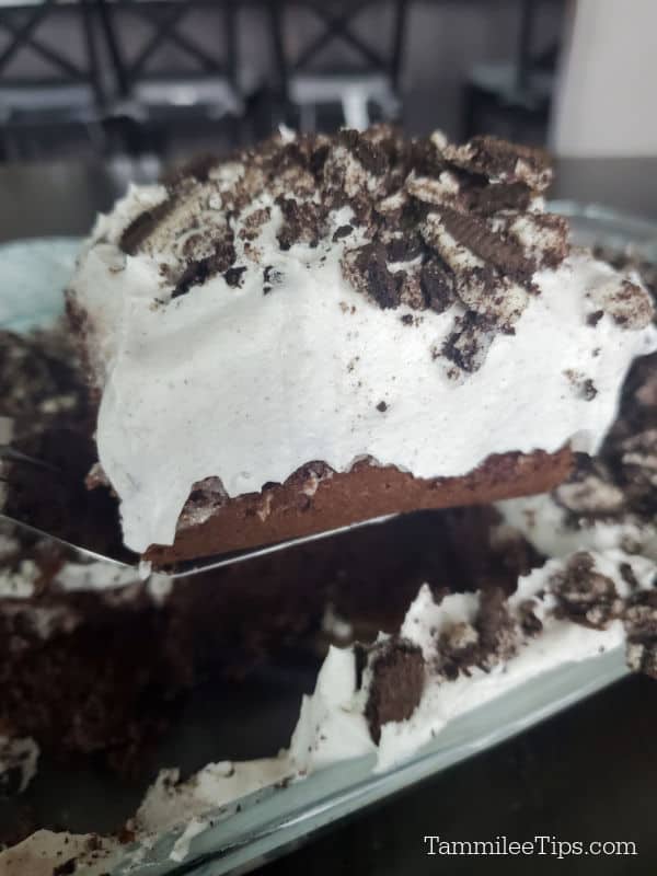 Spatula holding a square of Oreo Poke Cake above the baking dish. 