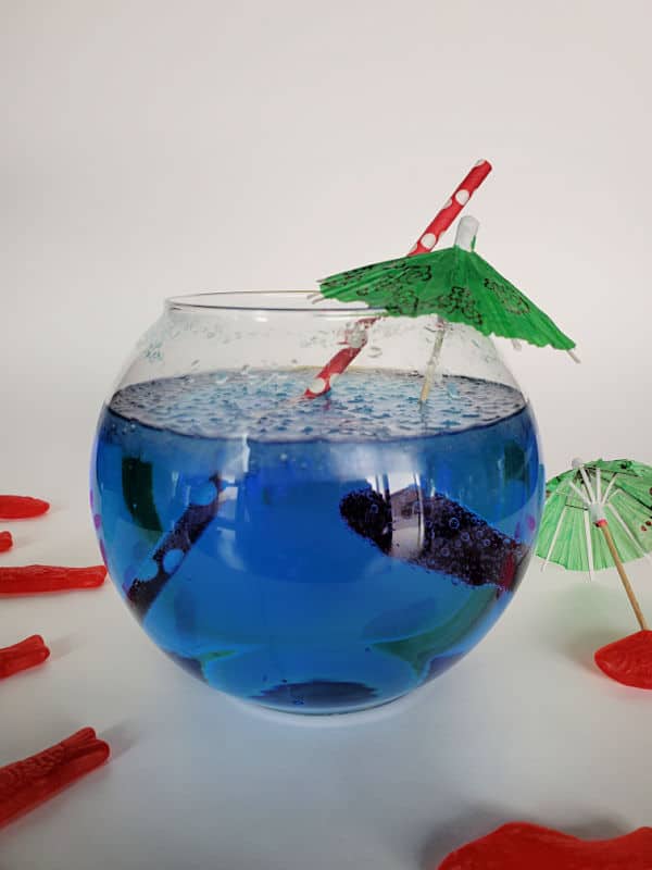 Blue Sonic Ocean Water Drink in a fishbowl with a green tropical umbrella and red straw with Swedish Fish