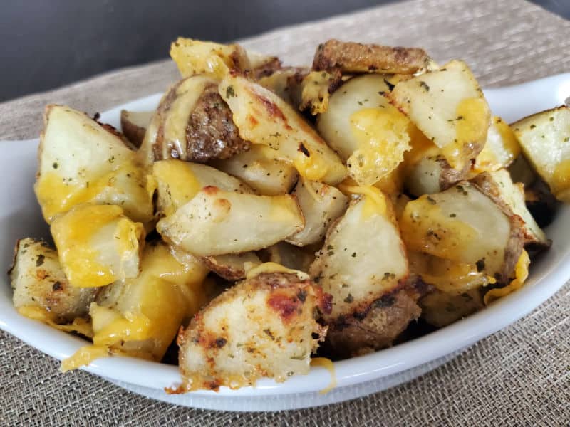 cheesy covered hidden valley ranch potatoes in a white baking dish on a placemat