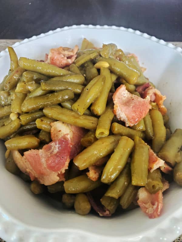 Southern style green beans and bacon steaming in a white serving bowl