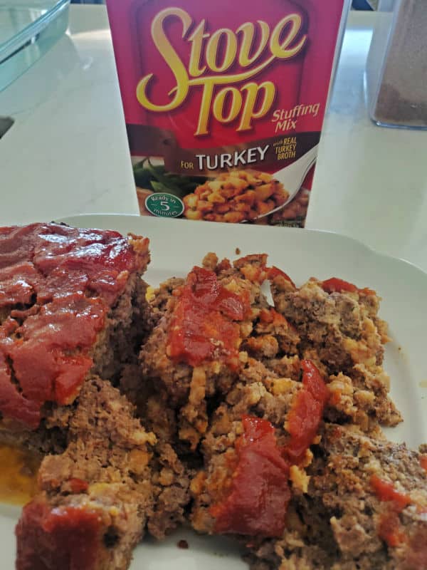 Stove Top stuffing box next to a white plate with slices of Stove Stop Stuffing. 