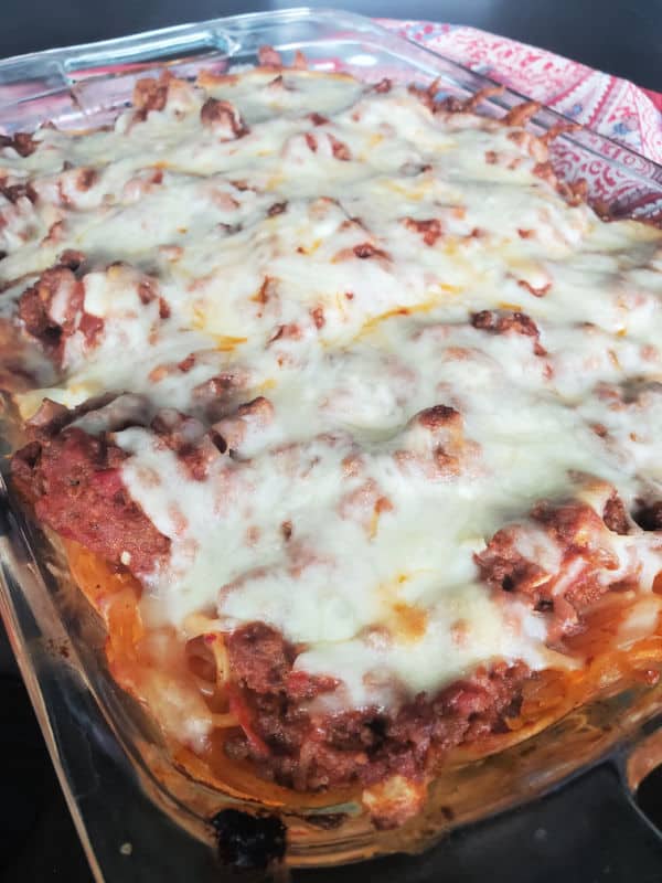 million dollar spaghetti casserole with melted cheese on top in a glass baking dish