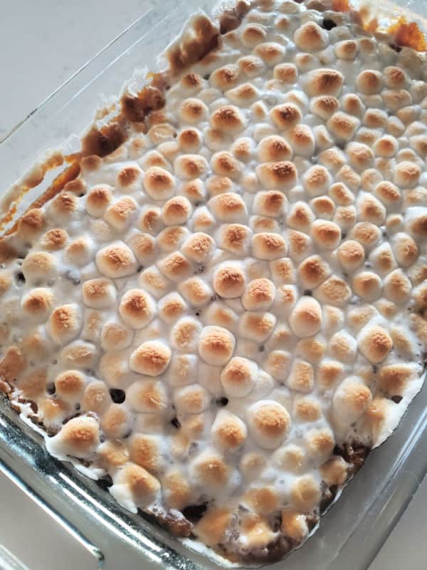 mini marshmallows toasted on top of sweet potatoes in a glass baking dish