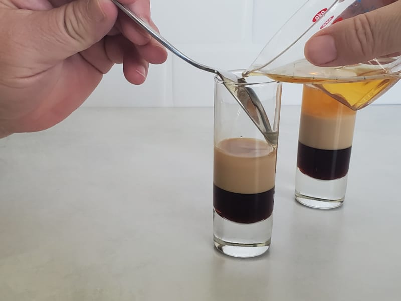 Grand Marnier pouring into a shot glass to complete a B52 Cocktail