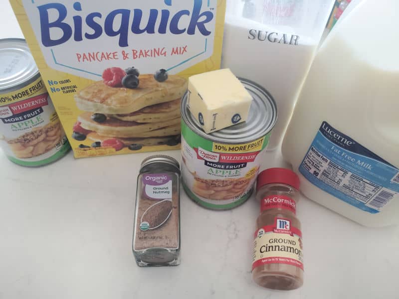 Apple pie filling, Bisquick Sugar, Butter, Nutmeg, Cinnamon, and milk on a white counter. 