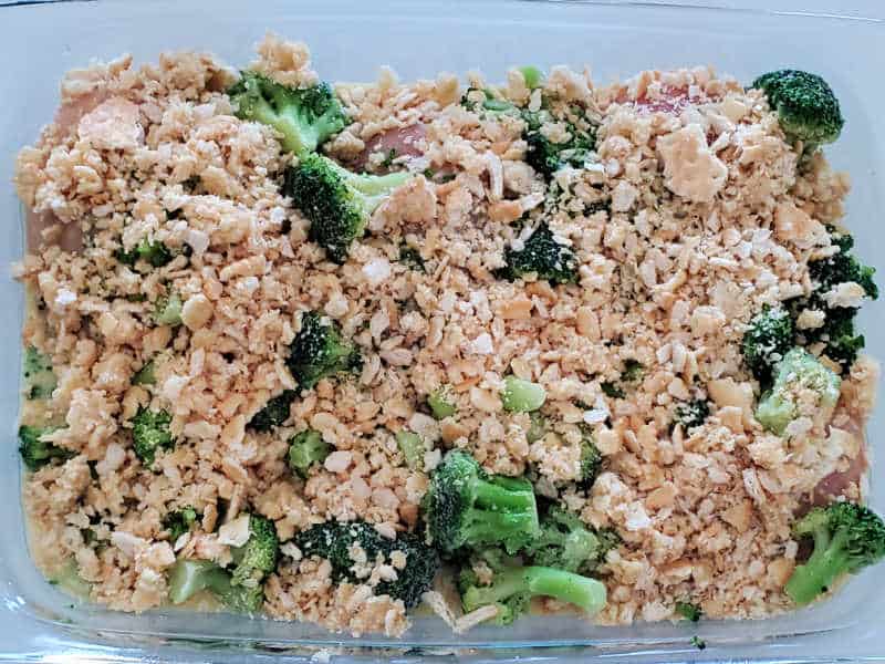 Ritz crackers covering broccoli and chicken in a glass baking dish. 