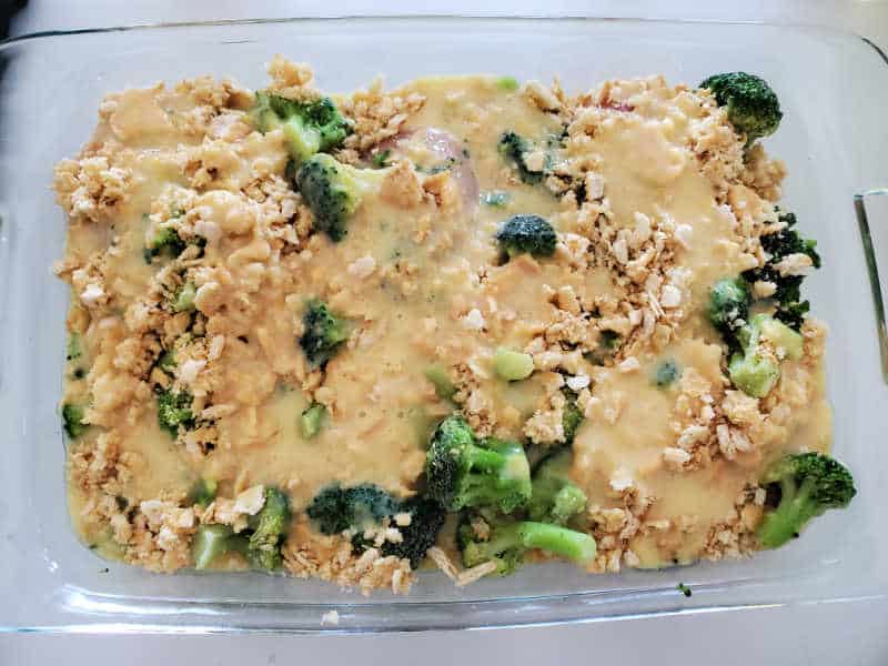 Soup mixture covering ritz crackers and broccoli in a glass baking dish