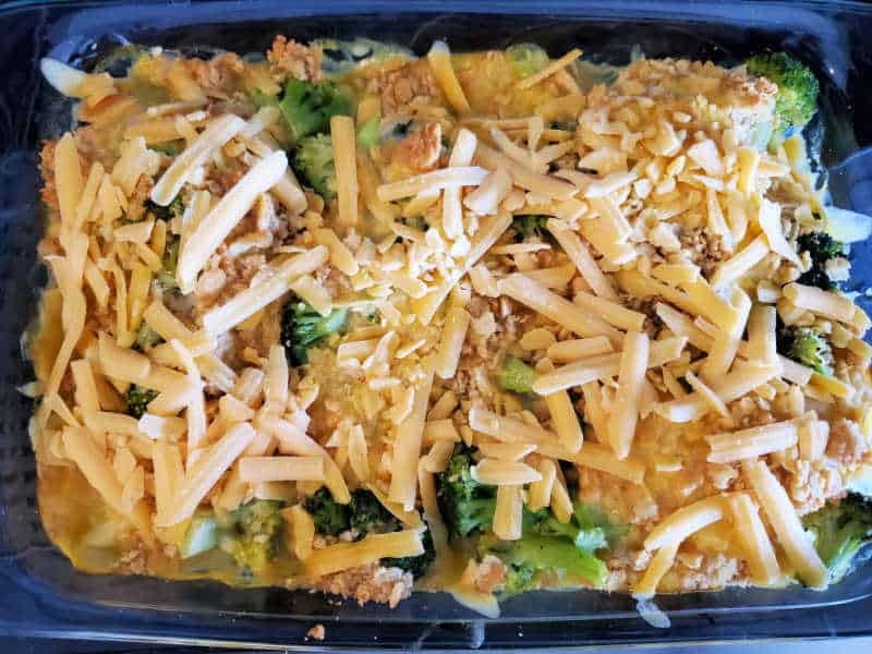 cheddar cheese spread over a baking dish with broccoli and ritz crackers 