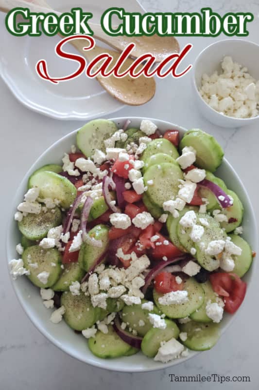 Greek Cucumber Salad on a white plate with feta cheese next to a plate with wooden spoons