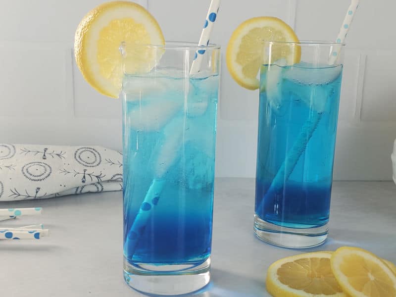 2 bright blue cocktails in tall glasses with lemon wheels, sex in the driveway cocktails