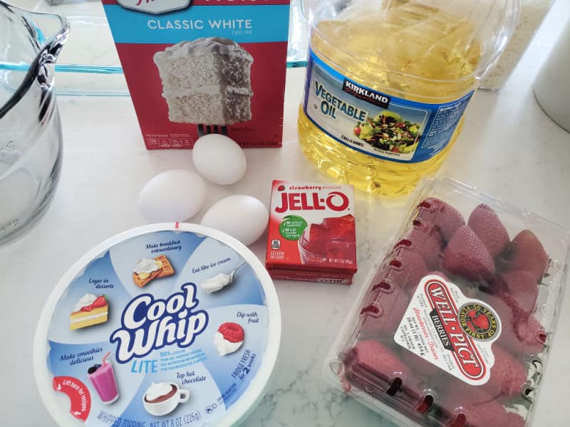 White cake mix, vegetable oil, eggs, Cool whip, Strawberry Jello, Strawberries, and a glass bowl 