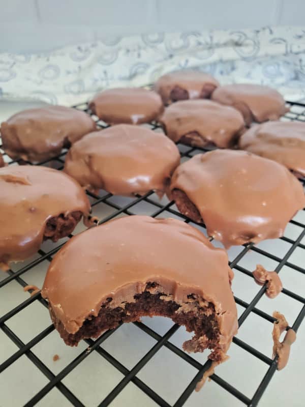 Texas sheet cake cookies on a drying rack with a bite taken out of a cookie