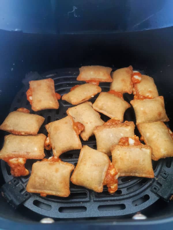 Air fried pizza rolls in a black air fryer basket. 