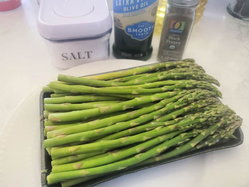 salt, olive oil, pepper, and fresh asparagus on a white counter