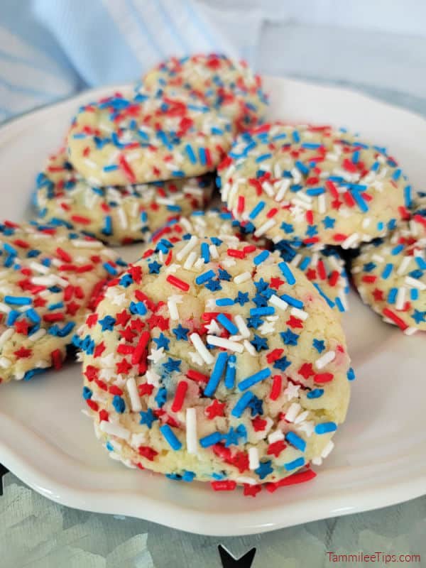 red white and blue sprinkle covered cookies stacked on a white plate