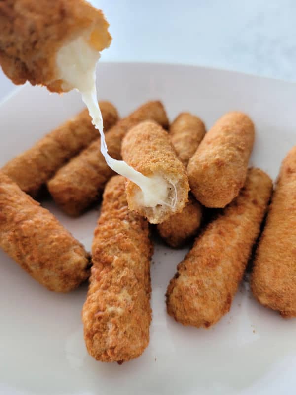 cheese pull from an air fried mozzarella stick on a white plate