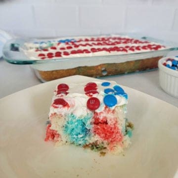 Red White and Blue Poke Cake square on a white plate next to a flag cake