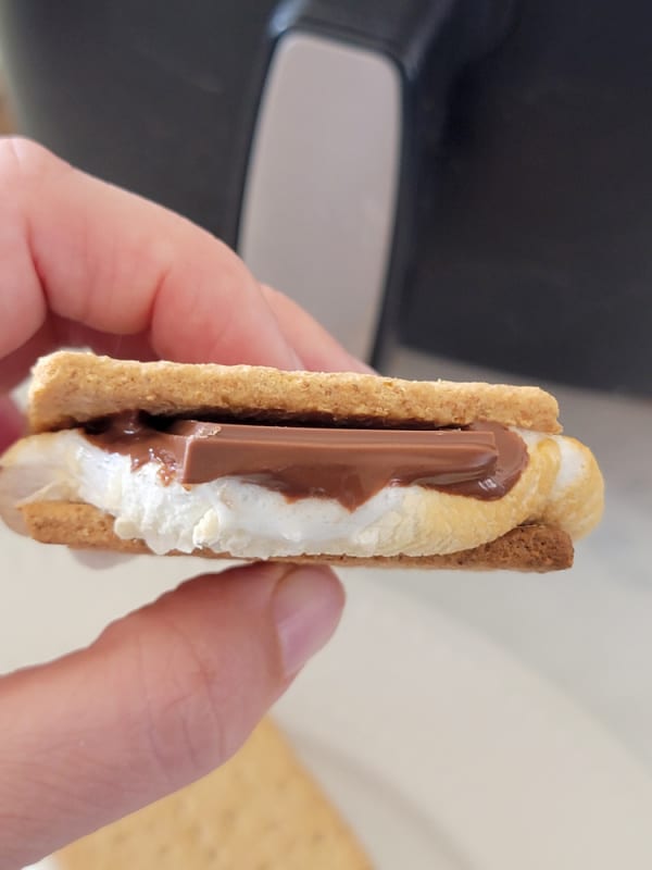 Hand holding a smores with melted chocolate 