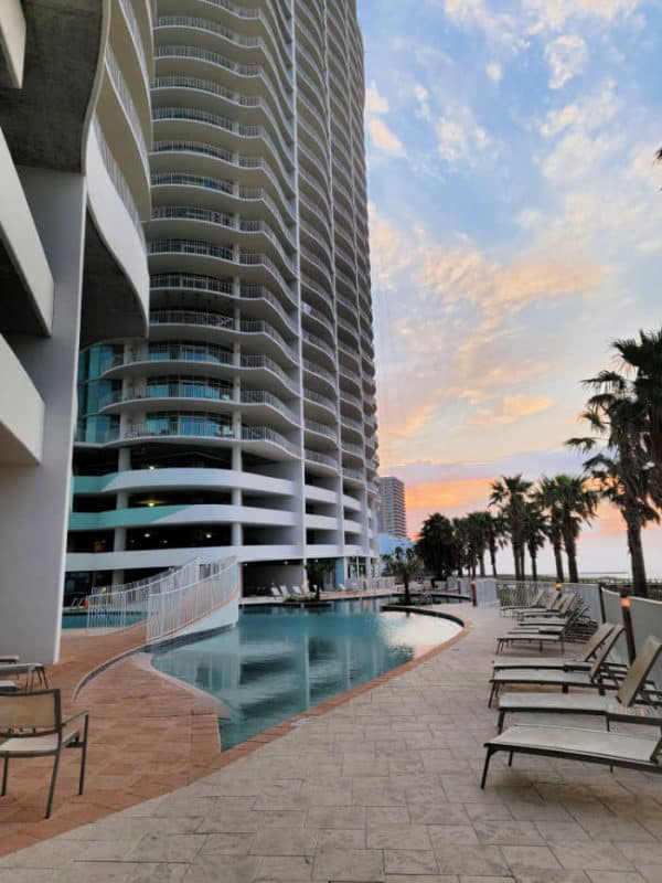 swimming pool with pool chairs below Turquoise Place condo building and palm trees