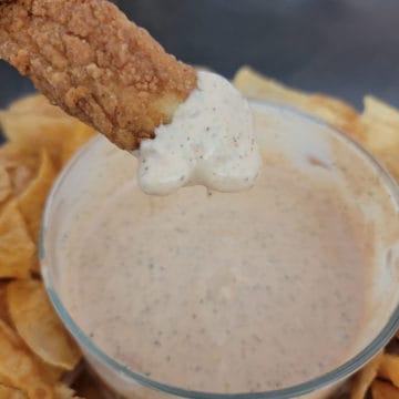 Chicken tender dipping into Zaxby's Sauce in a glass bowl