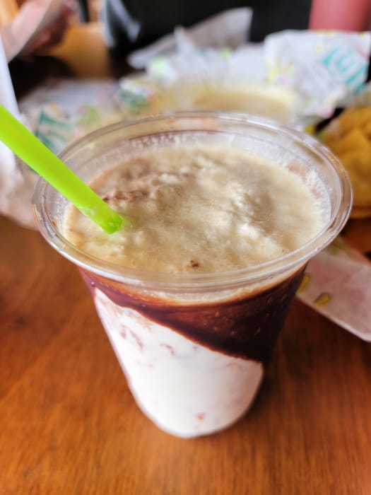 Frozen bushwacker drink in a plastic cup with a green straw