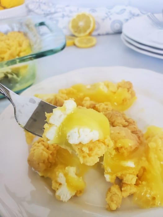 Lemon dump cake piece on a fork above a plate